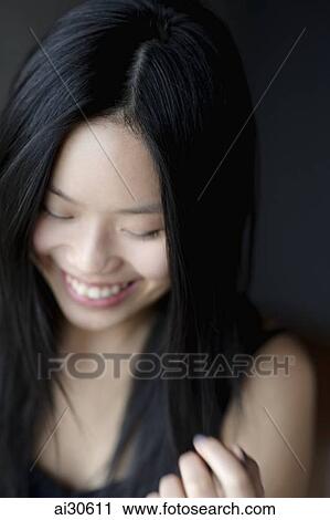 Head shot of young woman smiling and looking down View Large Photo Image Stock Image - Head shot of young woman smiling and looking down. Fotosearch