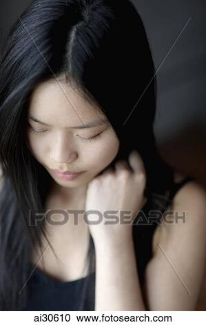 Stock Image - Head shot young woman looking down. Fotosearch