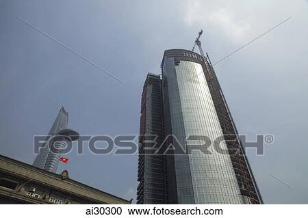Stock Image - Low angle of modern skyscraper being built and Bitexco Financial Tower in background. Ho Chi Minh, Vietnam. Fotosearch