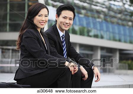 Man and woman wearing business attire sitting outdoors and smiling at camera View Large Photo Image Stock Photo - Man and woman wearing business attire sitting outdoors and smiling at camera. Fotosearch
