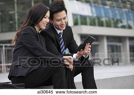 Man and woman wearing business suits looking at a digital tablet View Large Photo Image Stock Photography - Man and woman wearing business suits looking at a digital tablet. Fotosearch