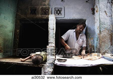 Man ironing clothes while his child naps, Varanasi, India View Large Photo Image Stock Image - Man ironing clothes while his child naps, Varanasi, India. Fotosearch