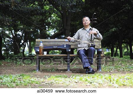 Man sitting on park bench playing the Erhu at Yoyogi Park, Harajuku, Japan View Large Photo Image Stock Photo - Man sitting on park bench playing the Erhu at Yoyogi Park, Harajuku, Japan. Fotosearch