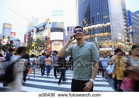 Man standing on busy street at dusk, Shibuya, Japan View Large Photo Image Stock Photograph - Man standing on busy street at dusk, Shibuya, Japan. Fotosearch
