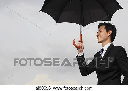 Man wearing a business suit holding a black umbrella. View Large Photo Image Stock Photograph - Man wearing a business suit holding a black umbrella.. Fotosearch