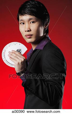 Stock Image - Man wearing a suit holding a deck of cards. Fotosearch