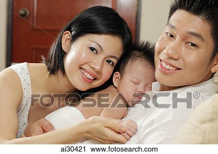 Mother and father holding their sleeping baby View Large Photo Image Stock Image - Mother and father holding their sleeping baby. Fotosearch