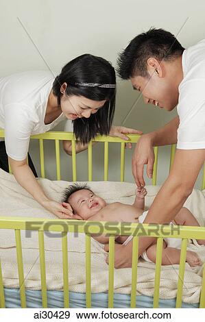 Mother and father playing with their baby View Large Photo Image Stock Photo - Mother and father playing with their baby. Fotosearch