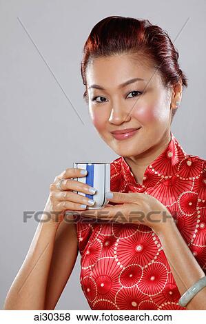 Stock Photo - Portrait of woman wearing Cheongsam and holding tea cup. Fotosearch