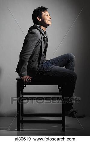 Profile on young man sitting on table and smiling. View Large Photo Image Stock Photo - Profile on young man sitting on table and smiling.. Fotosearch