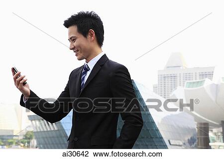 Stock Image - Profile shot of man in business suit looking at a phone. Fotosearch