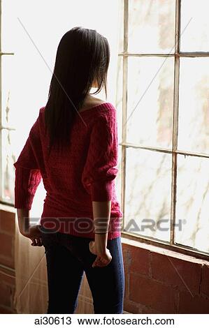 Stock Image - Rear view of woman looking out the window. Fotosearch