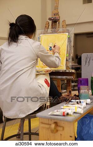 Picture - Rear view of young woman painting on an easel. Fotosearch