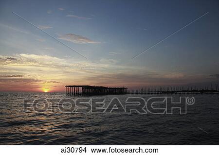 Picture - Sun setting in the ocean with pier in foreground, Cambodia. Fotosearch