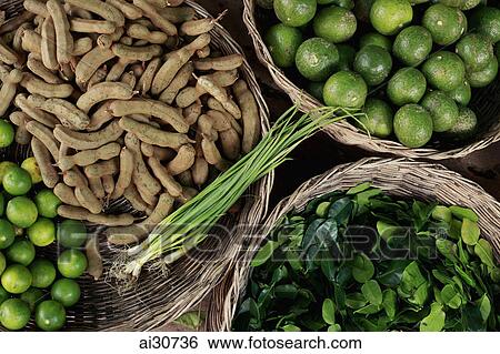 Stock Photograph - Tamarind, limes, green onions and curry leaves in baskets, Cambodia. Fotosearch