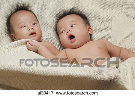 Twin babies wrapped up in a blanket together View Large Photo Image Stock Photo - Twin babies wrapped up in a blanket together. Fotosearch