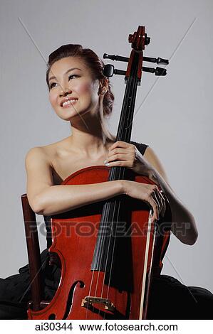 Picture - Woman holding a cello and smiling. Fotosearch