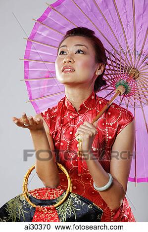 Woman holding a Chinese umbrella holding her hand out to check for rain View Large Photo Image Stock Image - Woman holding a Chinese umbrella holding her hand out to check for rain. Fotosearch