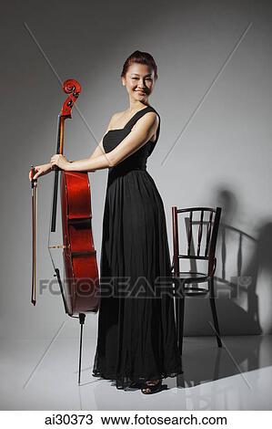 Woman in long black dress holding a cello. View Large Photo Image Stock Image - Woman in long black dress holding a cello.. Fotosearch