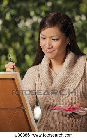 Woman painting on an easel outdoors View Large Photo Image Stock Photograph - Woman painting on an easel outdoors. Fotosearch