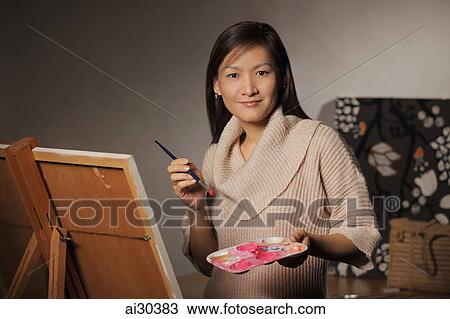 Stock Image - Woman painting on an easel.. Fotosearch