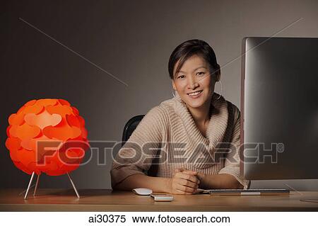 Stock Photography - Woman sitting at a desk working at a computer. Fotosearch