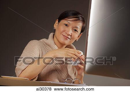 Woman sitting at desk holding coffee cup. View Large Photo Image Stock Photo - Woman sitting at desk holding coffee cup.. Fotosearch