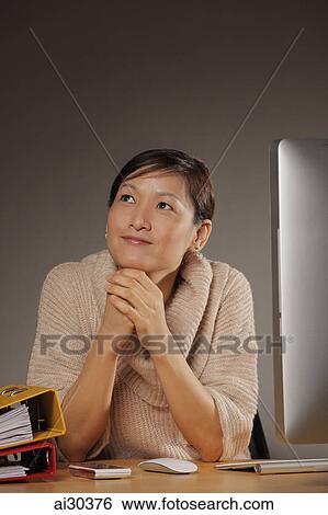 Woman sitting at desk looking up. View Large Photo Image Stock Photograph - Woman sitting at desk looking up.. Fotosearch