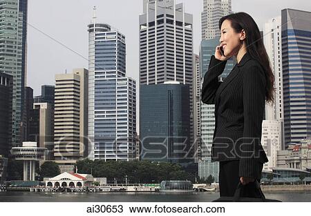 woman wearing a business suit standing in front of buildings and talking on the phone. View Large Photo Image Stock Image - woman wearing a business suit standing in front of buildings and talking on the phone.. Fotosearch