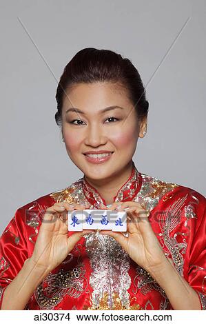 Picture - Woman wearing Cheongsam holding Mahjong tiles with the characters for "South, East, West, North". Fotosearch