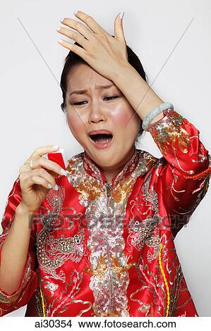 Woman wearing Chinese jacket and holding Mahjong tile looking upset. View Large Photo Image Picture - Woman wearing Chinese jacket and holding Mahjong tile looking upset.. Fotosearch