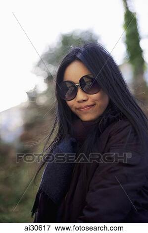 Woman wearing large sunglass and smiling outdoors View Large Photo Image Stock Photo - Woman wearing large sunglass and smiling outdoors. Fotosearch