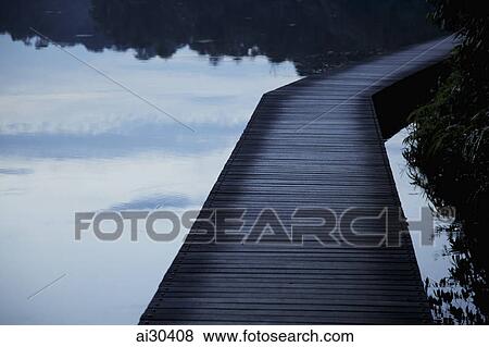 Wooden path over a lake in the evening View Large Photo Image Stock Photo - Wooden path over a lake in the evening. Fotosearch