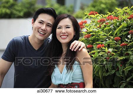 Stock Photo - Young couple sitting together outside smiling.. Fotosearch