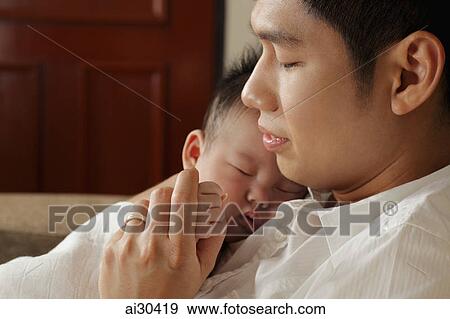 Stock Photo - Young father holding his sleeping baby.. Fotosearch