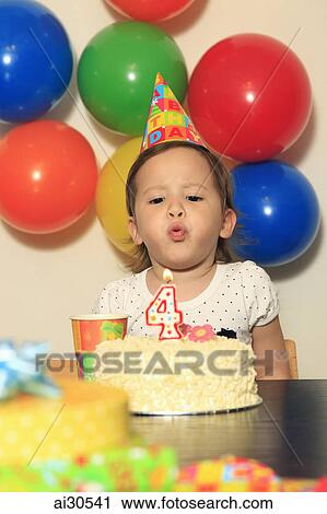 Stock Image - Young girl blowing out a candle on her birthday cake. Fotosearch