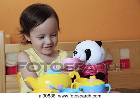 Stock Photo - Young girl having a tea party with her toy panda bear. Fotosearch