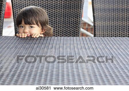 Young girl peering over a table View Large Photo Image Stock Image - Young girl peering over a table. Fotosearch