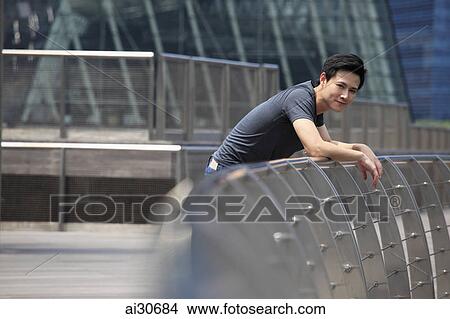 Picture - Young man leaning on railing smiling. Fotosearch