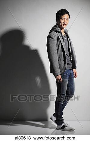 Stock Photo - Young man smiling and wearing a hooded sweatshirt.. Fotosearch