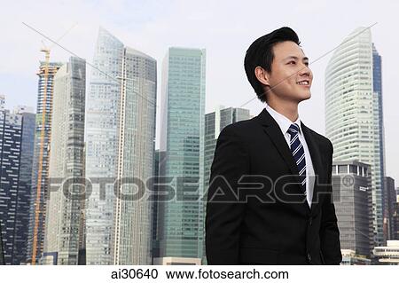 Young man standing in front of buildings looking up View Large Photo Image Stock Image - Young man standing in front of buildings looking up. Fotosearch