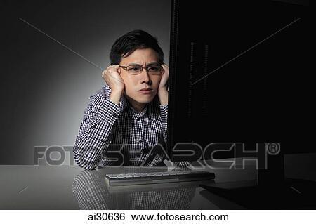 Young man staring at computer looking worried View Large Photo Image Stock Photograph - Young man staring at computer looking worried. Fotosearch