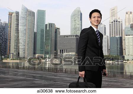 Stock Photo - Young man wearing a business suit standing in front of buildings.. Fotosearch