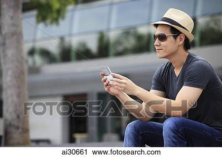 Young man wearing a hat and looking at phone. View Large Photo Image Stock Image - Young man wearing a hat and looking at phone.. Fotosearch