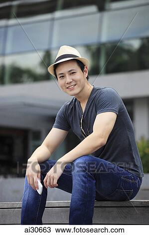 Stock Image - Young man wearing a hat and smiling at camera.. Fotosearch