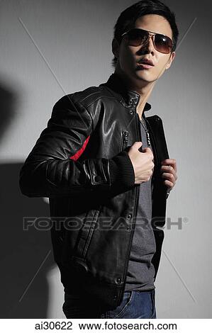Stock Image - Young man wearing sunglasses and leather jacket.. Fotosearch