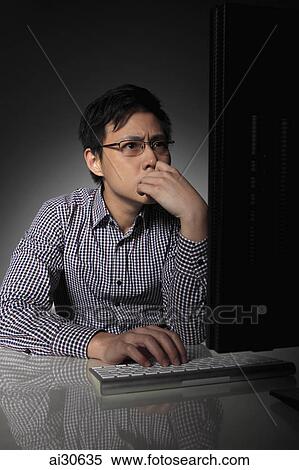 Young man working on computer looking worried View Large Photo Image Stock Photography - Young man working on computer looking worried. Fotosearch