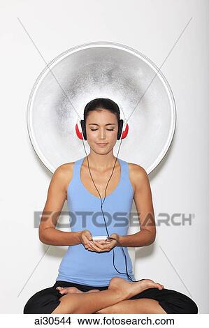 Young woman meditating while listening to music View Large Photo Image Picture - Young woman meditating while listening to music. Fotosearch