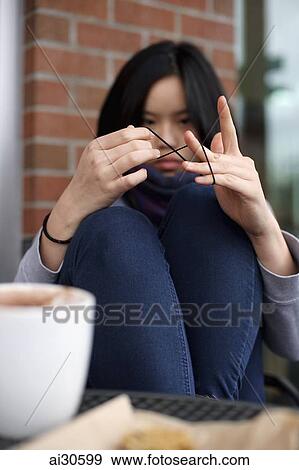 Young woman sitting at a cafe, playing with string View Large Photo Image Stock Photo - Young woman sitting at a cafe, playing with string. Fotosearch