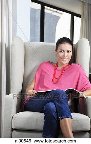 Young woman sitting in a comfy chair and reading a book. View Large Photo Image Stock Photograph - Young woman sitting in a comfy chair and reading a book.. Fotosearch